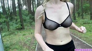 Плавокоса жена вежба напољу у парку, откривајући своје голо тело и поскакујући грудима