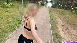 Una donna bionda fa esercizi all'aperto nel parco, mostrando il suo corpo nudo e facendo rimbalzare il suo seno